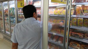 Fiscal da vigilância sanitária recolhendo produtos em um dos supermercados alvos da série de inspeções. (Foto: Sesau)